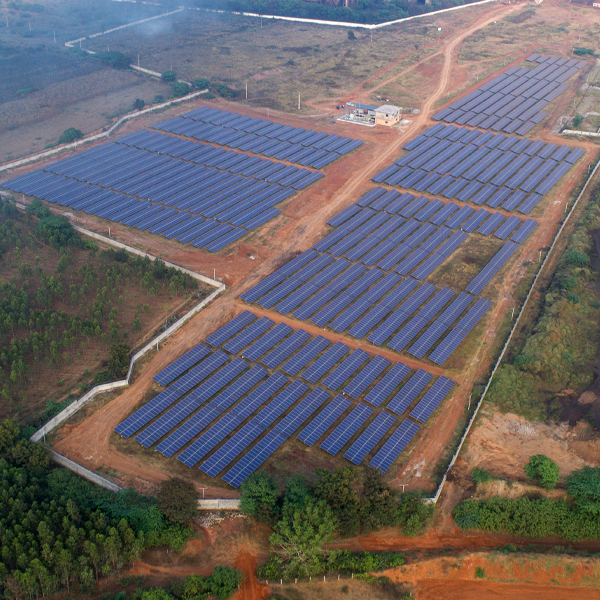 An aerial view of a vast ground mounted solar farm, showcasing rows of solar panels arranged in a rectangular pattern.